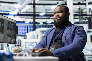 Afrika-Amerika güneş paneli uzmanı yüksek teknolojili bir üretim tesisinde, kalite kontrolü ve kurumsal altyapı denetimini yansıtan operasyonel verileri inceliyor. Fotovoltaikler.