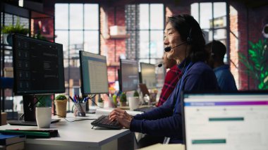 Çağrı merkezinde teknik destek uzmanı. Kulaklık, bilgisayar çalışma istasyonu ve kamera B kullanılarak adım adım müşteri bağlantıları sorunu çözülüyor.