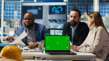 Fabrika mühendisleri kroma anahtar dizüstü bilgisayar kullanarak üretim planlarını rafine ediyorlar. Uzmanlar, izole ekran defteri, kamera B kullanılarak prototipler için endüstriyel fabrika yapılandırmalarını özetliyor