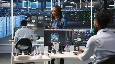 Sunucu merkezindeki kadın, sistem sağlığını optimize etmek için tablet cihazında yapay zeka görselleme öngörüleri kullanıyor. Veri merkezi bilgisayar bilimcisi düğüm ağacı araçları kullanarak altyapı sorunlarını analiz ediyor, kamera A