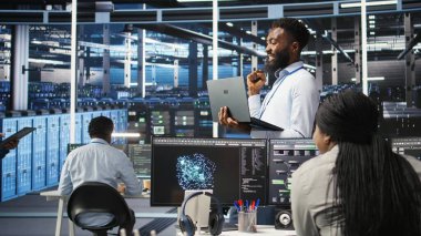 Happy Veri Merkezi Yöneticisi dizüstü bilgisayarda düğüm ağacı programlama kullanır, iş arkadaşıyla beşlik çakar. Gülümseyen sunucu çiftliği çalışanı iş arkadaşını selamlıyor, veri analiz grafiğini inceliyor, kamera A