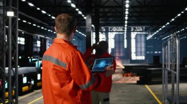 Mühendis, üretim ve imalat görevlerini denetlerken, sinirsel ağ simülasyon verilerini gözden geçirirken, üretim tesisinde tablet üzerinde yapay zeka araçları kullanmaktadır. Kamera A.