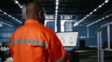 Afrikalı Amerikalı teknisyen, robot yazılım modelini imalat tesisinde, üretim görevlerinde ve ekipman operasyonunda inceledi. Çelik makineli ağır endüstri, varlık yönetimi. Kamera B.