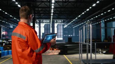 Fabrika zeminindeki makineleri izlemek için yapay zeka sistemini kullanan işçiler, endüstriyel çevrede ağır teknoloji ve mühendislik gelişimini gösteriyor. Kamera A.