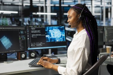 Veri merkezindeki yönetici kullanıcı teknik desteği sağlar, işlemleri etkileyen ağ hatalarını düzeltir. Sunucu merkezi çalışanı mikrofonla konuşuyor, canlı destek aramalarını yönetiyor, müşterilere yardım ediyor.