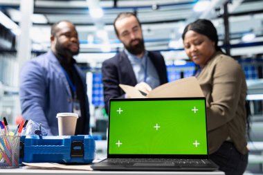 Profesyonel mühendislik grubu kroma anahtarının yanındaki güneş panellerini inceleyerek yeşil teknoloji ve çevre dostu yenilenebilir enerjide birlik gösteriyor. Üretim endüstrisinde operasyonel liderlik.