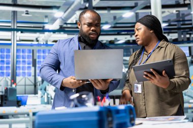 Üretim denetimi sırasında güneş paneli sistemlerini analiz eden bir grup endüstri uzmanı ve mühendis mühendislik mühendisliği doğruluğu, kalite kontrolü ve fabrika faaliyetlerinin verimliliğini güvence altına alıyor.
