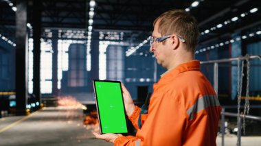 Siyah personelle dikey krom anahtar, fabrikada koruyucu teçhizatlarla çalışır, fabrika katındaki ekipmanlarla lojistik koordinasyonu destekler. Ağır metal işletim görevleri.