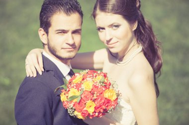 Happy just married bride and groom on green grass background