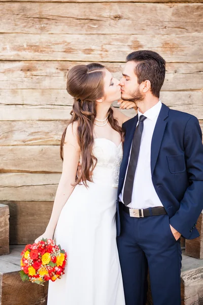 Noiva e noivo beijando no fundo wodden — Fotografia de Stock