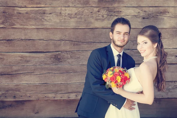 Smiling bride and groom on wooden background — Stockfoto