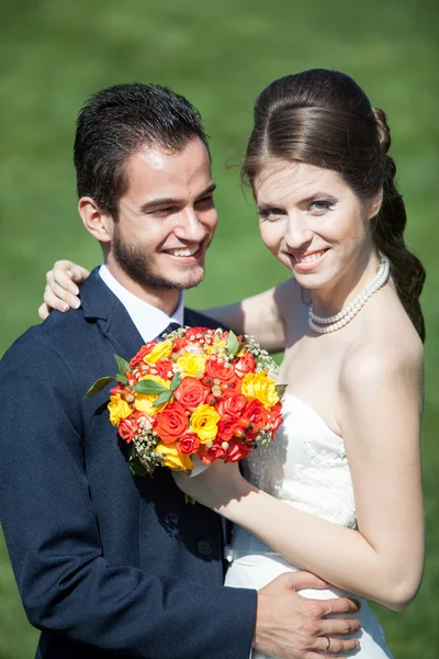 Happy just married bride and groom on green grass background — Stock Fotó