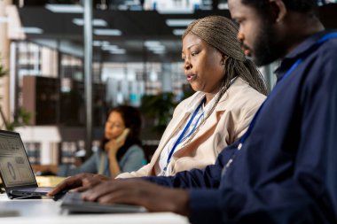 Genç çalışan ve yönetici, bilgisayar verilerini incelemek, hedefleri tartışmak ve idari görevleri çözmek için çözümler üretmek üzere masada toplandı. İş hedefleri ve kilometre taşlarının hizalanması.