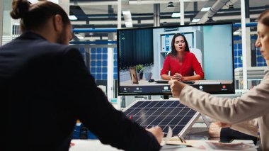 Ofisteki yöneticiler internet video görüşmesi sırasında güneş teknolojisi raporlarını inceliyorlar. Uzak telekonferans toplantısındaki hissedarlar yeşil enerji üretimindeki yatırım fırsatlarını tartışıyorlar, kamera A
