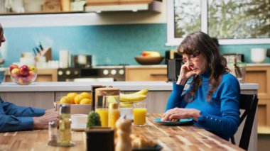 Olgun eş, yaşlı adam konuşmaya devam ederken rahatsız ve ilgisiz hissediyor. Evde emeklilikte monotonluk ve ilişki gerginliğinin yoğun ruh hali altını çiziyor. Kamera B.