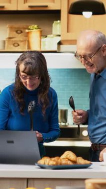 Dikey Video Aşırı neşeli yaşlı evli çift karaoke söylüyor ve mutfakta kendilerini genç hissediyorlar, pozitif enerji ve eğlence. İnsanlar sevgi dolu bir bağ kurup keyifli bir ortam yaratıyorlar.