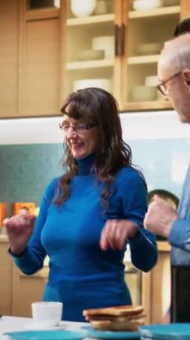 Dikey Video Oynatıcı yaşlı insanlar mutfakta dans ediyor ve sabah müziğinin tadını çıkarıyor. Romantik tutku, mutluluk ve evde sevgi dolu bir ilişkinin güzelliğini gösteren havalı ve şapşal hareketler. Kamera.