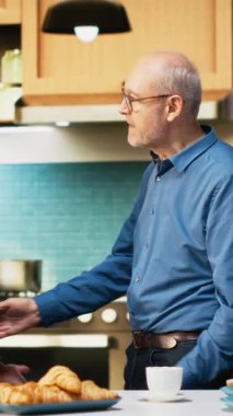 Dikey Videoda gülümseyen yaşlı karı koca mutfakta romantik bir dansı paylaşıyor, tutkulu bir aşk şarkısında vals yapıyor ve birbirleriyle flört ediyorlar. El ele tutuşmak ve yavaşça dans etmek, sallanmak