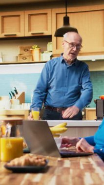 Dikey Video Evli insanlar sohbet ediyor ve haberlere birlikte bakıyorlardı mutfakta, taze kahve içiyorlardı ve evde sohbet ediyorlardı. Rahat bir aile sabahı boyunca rahat bir an.