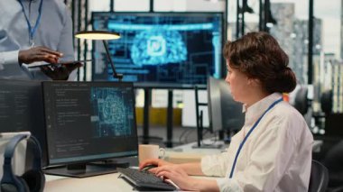 Yönetici ofisteki stajyer ile konuşuyor, karmaşık yapay zeka hesaplamalarını hızlandırmak için özel donanım kullanıyor. Takım lideri öğrenciye makine öğrenme eğitim verilerini nasıl yöneteceğini öğretiyor, kamera B