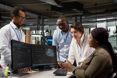 Team of technicians in office automating repetitive tasks using AI scripts on PC. Teamworking startup colleagues use artificial intelligence tech on computer to speed up feature implementation