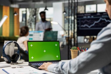 Dizüstü bilgisayardaki iş istatistiklerini gözden geçiren izole bir model şablonu olan beyaz erkek. Modern ofiste yeşil ekran gösteren dijital cihaz kullanan Kafkas finansal analist.