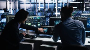 Veri merkezi sistem yöneticileri AI LLM kullanarak sinirsel ağı izlemek için PC kullanır. Asyalı adam ve iş arkadaşı sunucuların makine öğrenmesini denetlemek için yapay zeka kullanıyor. Kamera A