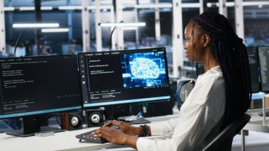Veri merkezi kadın programcısı, veri tabanlarını analiz etmek için makine öğrenme algoritmaları kullanıyor. Sunucu çiftliğindeki Afrikalı Amerikalı kadın yapay zeka nöro ağlarını kullanarak veri kalıplarını tanıdı, kamera A