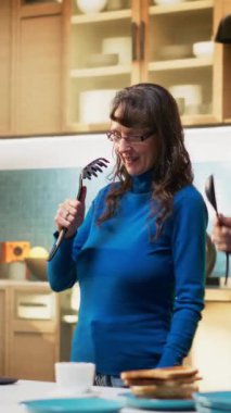 Dikey Video Enerjisi kıdemli erkek ve kadın mutfakta şarkı söylüyor ve gülüyor, emekliliklerinde müzik eşliğinde rahat bir sabah geçiriyorlar. Eğlenceli romantik aktiviteler aşk ve modern yaşam tarzını gösterir.