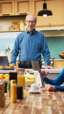 Son sınıf öğrencisinin ev mutfağında kahve ve hamur işi eşliğinde dinlenirken çekilmiş dikey video görüntüsü. Rahatlamış refah, neşeli yaşam tarzı ve emekli olmanın sakin havası.