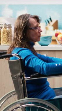 Kronik sakatlığı olan dikey Videolu Kadın kahvaltıda kocasıyla kahve servisi yapıyor, rahatlamış bir sabah rutininde birlikte gülüyor ve sohbet ediyorlar. Neşeli emekli yaşam tarzı evde, mutfak masasında