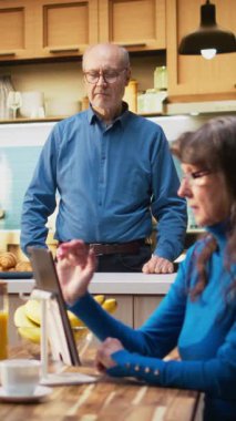 Dikey videolu yaşlı koca mutfakta gülümsüyor ve sıcak içkinin tadını çıkarıyor. Emekli hayatın doğal portresi huzurlu yaşam tarzını ve evdeki konforu, emekliliği yakalıyor.