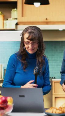 Dikey Videolu Neşeli karı koca mutfakta en sevdikleri şarkıyı söylüyor ve emekliliklerinde müzikle sabahlarının tadını çıkarıyorlar. İnsanlar mutfak aletlerini mikrofon olarak kullanıp gülüyorlar. Kamera B.