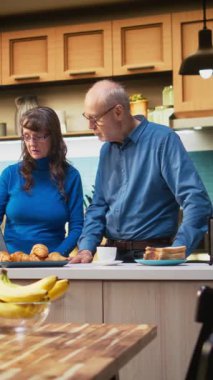 Dikey Videolu Karı-Koca, ev mutfağında dizüstü bilgisayar uygulamalarına bakıp kahvenin ve huzurlu bir rahatlığın tadını çıkarıyorlar. Neşeli yaşam tarzı, mutlu yaşam ve emeklilikte rahat anlar.