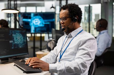 Uzman bilişim uzmanı yapay zeka teknolojisi kullanarak uzaktan tanı koyuyor, ofisteki teknik arızaları gideriyor. Destek biletlerini yöneten, mikrofonla konuşan.