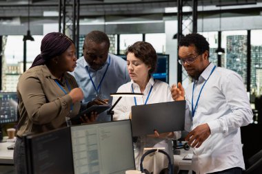 Yapay zeka mühendisliği ekibi ofiste yazılım geliştiriyor. Dizüstü bilgisayardaki sistem performans ölçümlerini analiz ediyor. Proje brifingi sırasında teknik yol haritası hakkında konuşan takım arkadaşları