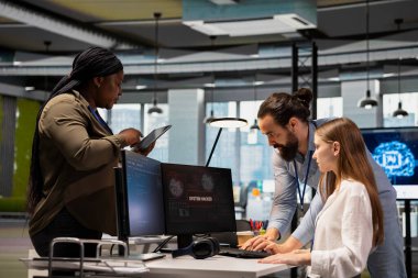 Meslektaşlar, ofis ekipmanlarını etkileyen ağ ihlallerini engellemek için genç işçilere yardım ediyor. Stajyere yardım eden bilişim personeli, PC 'de canlı siber saldırı uyarısına yanıt veriyor.