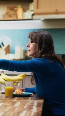 Dikey Video Yaşlısı çift, sağlıklı ev yapımı kahvaltı, hamur işi yemek ve kahve içmek suretiyle doğal sabah rutininin keyfini çıkarıyorlar. Karı koca samimi bir an için gündelik bir konuşma yapıyorlar. Kamera B