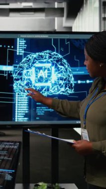 Yatırımcılar için sunum yapan dikey video teknisyeni yapay zekaya derin dalış yapmak için toplantı odasında toplandı. Afro-Amerikalı kadın yapay zekada yenilikler sergiliyor