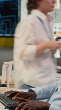 Ofisteki dikey video veri bilimcisi yeni özellikler başlatmak için yazılım geliştiriyor. Başlangıçta bilgisayar programları yazan, kod testi yapan ve kalite güvencesi veren Afro-Amerikan bir adam.