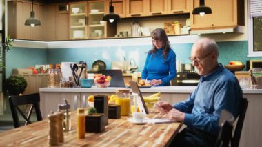 Mutfaktaki neşeli yaşlı emeklinin portresi gevşemiş yemek ve kahve fincanı gösteriyor. Huzurlu bir emeklilik hayatını doğal bir şekilde benimsiyor. Kamera A.