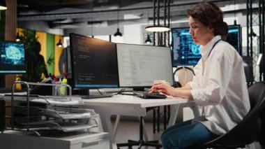 Ofiste çalışan neşeli teknisyen karmaşık yapay zeka hesaplamalarını hızlandırmak için özel donanım kullanıyor. Makine öğrenme eğitim verileri için gelişmiş bilişim uzmanı yönetim sistemleri, kamera A