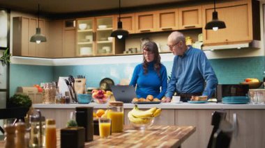 Yıllanmış karı koca evlerinin mutfağında dizüstü bilgisayar uygulamalarına göz atıyorlar, kahve ve huzur içinde dinlenmenin tadını çıkarıyorlar. Neşeli bir yaşam tarzı, mutlu bir yaşam ve emeklilikte rahat anlar. Kamera A.