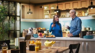 Olgun bir çift kahve servisi yapıyor ve mutfakta gülümsüyor. Huzurlu aile rutininin tadını çıkarıyorlar. Doğal ifadeler neşeli yaşam tarzını, refahı ve birlikte emekliliği yansıtıyor. Kamera A.