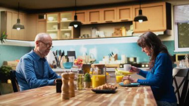 Üst düzey emekli erkek, dizüstü bilgisayarında web sayfalarını karıştırıyor ve karısı ona mola sembolünü gösteriyor, emeklilik hobilerine kızıyor. Kocası kahvaltıda bir kadını görmezden geliyor. Kamera A.