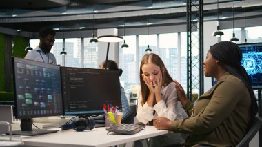 Çalışan, işteki üzgün arkadaşına yardım ediyor, iş arkadaşını rahatlatıyor, elini omzuna koyuyor. Üzgün genç kız masadaki nazik meslektaşıyla konuşuyor, duygusal destek alıyor, kamera A