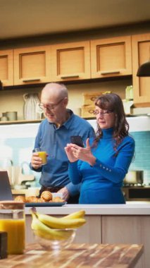 Akıllı telefondan internet sitelerinde gezinen, mutfakta gülümseyen, kahveyle rahatlayan ve huzurlu emeklilik hayatının tadını çıkaran son sınıf öğrencisi bir kadın. Emeklilik, pozitif yaşam tarzı ve sabah