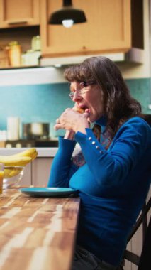 Yaşlı adam sohbete devam ederken dikey videolu olgun eş rahatsız ve ilgisiz hissediyor. Evde emeklilikte monotonluk ve ilişki gerginliğinin yoğun ruh hali altını çiziyor. Kamera A.