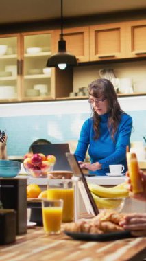 Dikey video yetişkin internette akıllı telefondan geziniyor ve mutfakta gülümsüyor, kahveyle rahatlıyor ve huzurlu emekliliğin tadını çıkarıyor. Emeklilik, pozitif yaşam tarzı ve doğal ev hayatı.