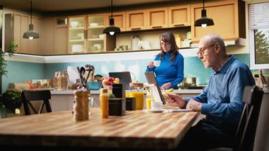 Huzurlu bir gülümsemeyle ev mutfağında duran yaşlı emekliler emekliliğin tadını çıkarıyorlar. Portre huzurlu refahı, sağlıklı yemek anlarını ve pozitif yaşam tarzını yansıtır. Kamera A.